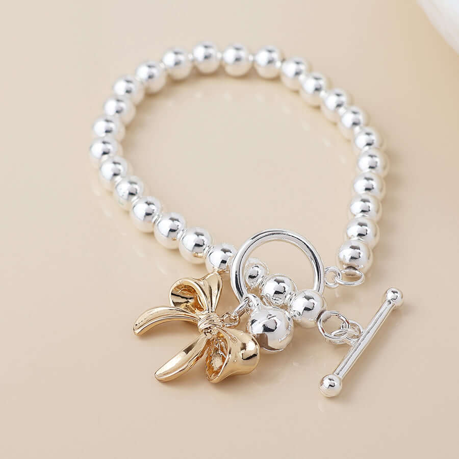 POM925 - Silver plated bell and golden bow charm bracelet