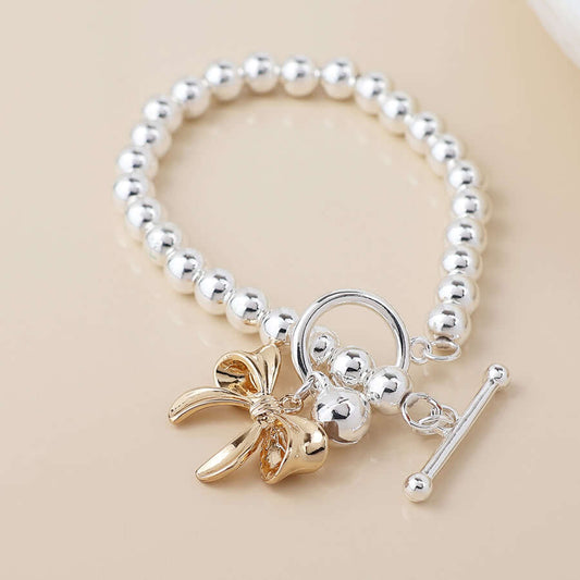 POM925 - Silver plated bell and golden bow charm bracelet