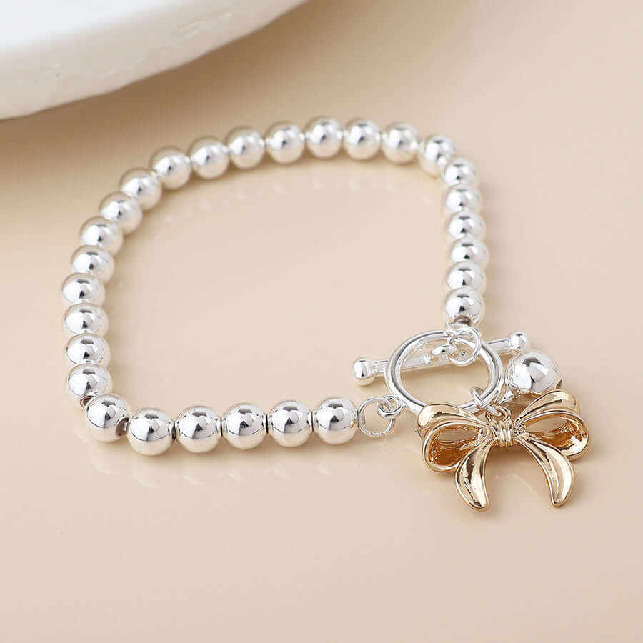 POM925 - Silver plated bell and golden bow charm bracelet